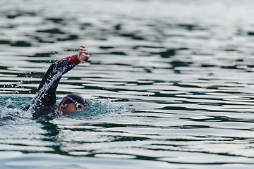 Image showing A professional triathlete trains with unwavering dedication for an upcoming competition at a lake, emanating a sense of athleticism and profound commitment to excellence.