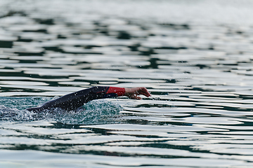 Image showing A professional triathlete trains with unwavering dedication for an upcoming competition at a lake, emanating a sense of athleticism and profound commitment to excellence.