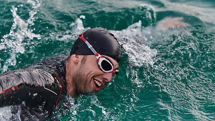 Image showing A professional triathlete trains with unwavering dedication for an upcoming competition at a lake, emanating a sense of athleticism and profound commitment to excellence.