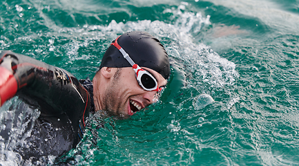 Image showing A professional triathlete trains with unwavering dedication for an upcoming competition at a lake, emanating a sense of athleticism and profound commitment to excellence.