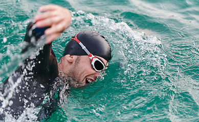 Image showing A professional triathlete trains with unwavering dedication for an upcoming competition at a lake, emanating a sense of athleticism and profound commitment to excellence.