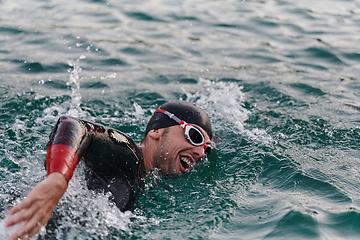 Image showing A professional triathlete trains with unwavering dedication for an upcoming competition at a lake, emanating a sense of athleticism and profound commitment to excellence.