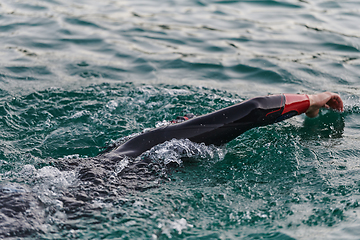 Image showing A professional triathlete trains with unwavering dedication for an upcoming competition at a lake, emanating a sense of athleticism and profound commitment to excellence.