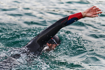 Image showing A professional triathlete trains with unwavering dedication for an upcoming competition at a lake, emanating a sense of athleticism and profound commitment to excellence.