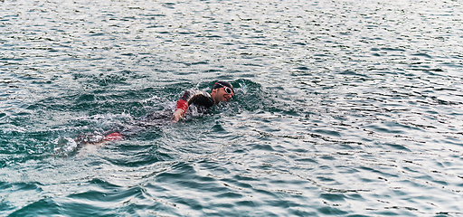 Image showing A professional triathlete trains with unwavering dedication for an upcoming competition at a lake, emanating a sense of athleticism and profound commitment to excellence.