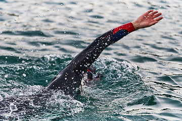 Image showing A professional triathlete trains with unwavering dedication for an upcoming competition at a lake, emanating a sense of athleticism and profound commitment to excellence.