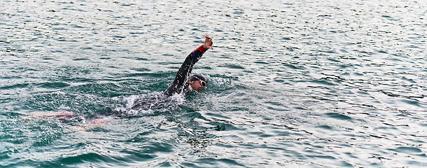 Image showing A professional triathlete trains with unwavering dedication for an upcoming competition at a lake, emanating a sense of athleticism and profound commitment to excellence.