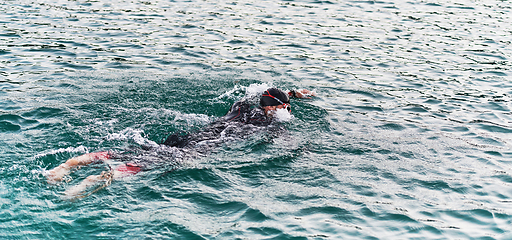 Image showing A professional triathlete trains with unwavering dedication for an upcoming competition at a lake, emanating a sense of athleticism and profound commitment to excellence.