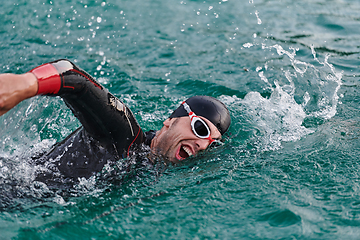 Image showing A professional triathlete trains with unwavering dedication for an upcoming competition at a lake, emanating a sense of athleticism and profound commitment to excellence.