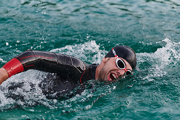 Image showing A professional triathlete trains with unwavering dedication for an upcoming competition at a lake, emanating a sense of athleticism and profound commitment to excellence.