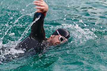 Image showing A professional triathlete trains with unwavering dedication for an upcoming competition at a lake, emanating a sense of athleticism and profound commitment to excellence.