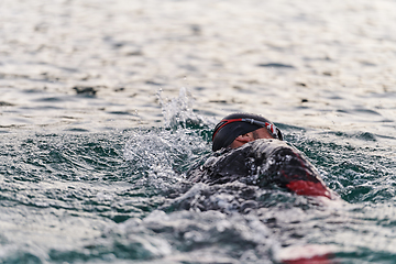 Image showing A professional triathlete trains with unwavering dedication for an upcoming competition at a lake, emanating a sense of athleticism and profound commitment to excellence.