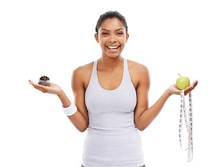 Image showing Portrait, woman and decision of an apple or cupcake in studio isolated on white background for fitness. Exercise, smile and choice with a happy young athlete holding a measuring tape to lose weight