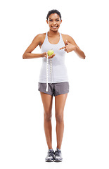 Image showing Woman, lose weight and pointing to measuring tape and apple in white background or studio. Indian, model and happy with results of fitness, wellness and diet with healthy food, nutrition and fruit