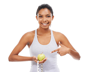 Image showing Woman, pointing and lose weight with a measuring tape and apple in white background or studio. Happy, model and healthy food for results in fitness, wellness and diet with nutrition and fruit