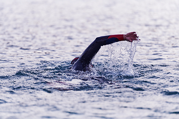 Image showing A professional triathlete trains with unwavering dedication for an upcoming competition at a lake, emanating a sense of athleticism and profound commitment to excellence.