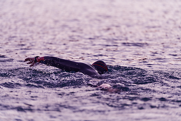 Image showing A professional triathlete trains with unwavering dedication for an upcoming competition at a lake, emanating a sense of athleticism and profound commitment to excellence.