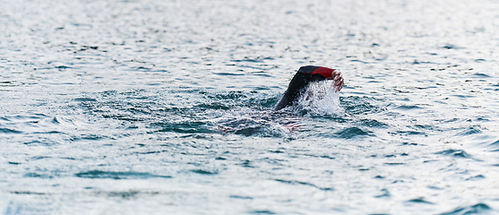 Image showing A professional triathlete trains with unwavering dedication for an upcoming competition at a lake, emanating a sense of athleticism and profound commitment to excellence.