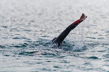 Image showing A professional triathlete trains with unwavering dedication for an upcoming competition at a lake, emanating a sense of athleticism and profound commitment to excellence.