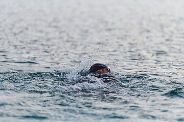 Image showing A professional triathlete trains with unwavering dedication for an upcoming competition at a lake, emanating a sense of athleticism and profound commitment to excellence.