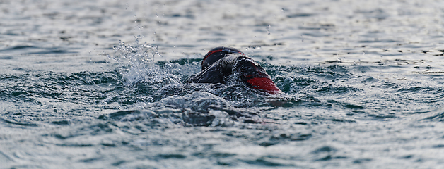 Image showing A professional triathlete trains with unwavering dedication for an upcoming competition at a lake, emanating a sense of athleticism and profound commitment to excellence.