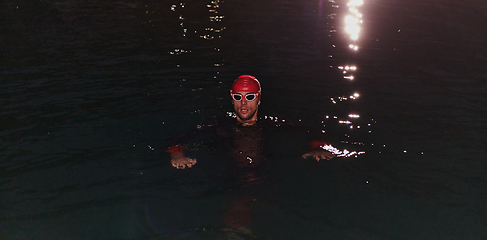 Image showing A determined professional triathlete undergoes rigorous night time training in cold waters, showcasing dedication and resilience in preparation for an upcoming triathlon swim competition