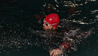 Image showing A determined professional triathlete undergoes rigorous night time training in cold waters, showcasing dedication and resilience in preparation for an upcoming triathlon swim competition