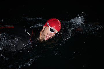 Image showing A determined professional triathlete undergoes rigorous night time training in cold waters, showcasing dedication and resilience in preparation for an upcoming triathlon swim competition