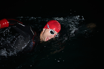 Image showing A determined professional triathlete undergoes rigorous night time training in cold waters, showcasing dedication and resilience in preparation for an upcoming triathlon swim competition