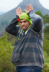 Image showing Mountain, funny hat and portrait of man in nature for camping, hiking and adventure outdoors. Comic, humor and person with bunny ears for joke on holiday, vacation and explore to travel wilderness