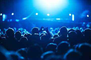 Image showing People, blue and crowd for concert, performance or stage in arena for rock, psychedelic or electric music. Lens flare, light and equipment with person, holding and smartphone for social media post