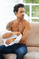 Image showing Fashion, body and a young man dressing on a sofa in the living room of his home while thinking in the morning. Clothes, style and casual with a shirtless male person getting ready in an apartment