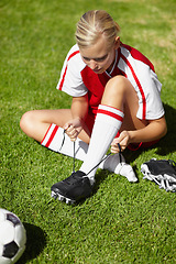 Image showing Girl, soccer and tie shoelace on field, safety and start training for fitness, health or competition on pitch. Person, shoes and football for preparation, ready or game for sport contest on grass
