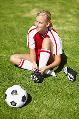 Image showing Woman, soccer and tie shoelace on field, safety and start training for fitness, health or competition on pitch. Girl, shoes and football for preparation, ready and thinking for sport contest on grass