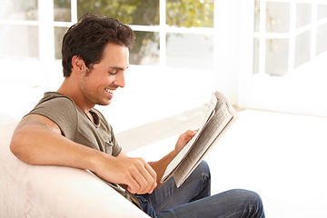 Image showing Man, reading and happy with newspaper on sofa for relax, morning break and information in living room. Person, face and smile for article, story and news on couch of apartment for headline or peace