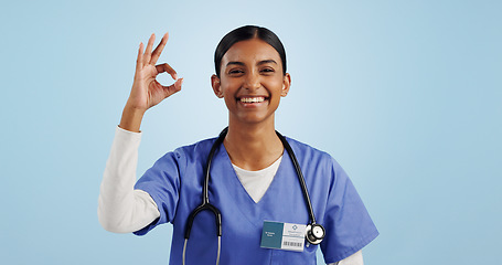 Image showing Happy woman, okay or portrait of doctor with smile, pride or confidence isolated on blue background. Wellness, perfect or healthcare worker with approval sign, success or yes hand gesture in studio