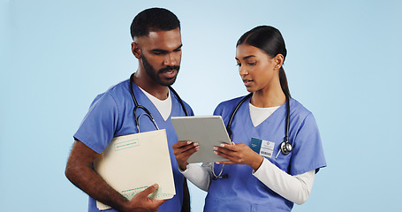 Image showing Healthcare, tablet and discussion with a medicine team in studio on a blue background for problem solving. Medical, technology or insurance with a man and woman nurse talking about a diagnosis report