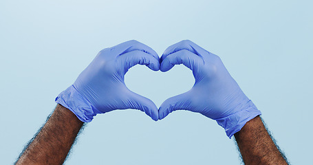 Image showing Man, doctor and heart hands with gloves for healthcare isolated against a blue studio background. Closeup of male person or medical nurse with like emoji, yes sign or shape for love or care on mockup