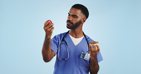 Image showing Doctor, apple and donut for health, diet or natural nutrition against a blue studio background. Man, medical nurse or surgeon with organic fruit and dessert in choice for wellness on mockup space