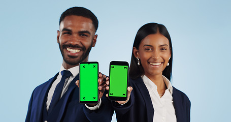 Image showing Business people, portrait and phone with green screen for advertising against a blue studio background. Businessman and woman employee showing mobile smartphone display, chromakey or mockup space