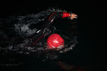 Image showing A determined professional triathlete undergoes rigorous night time training in cold waters, showcasing dedication and resilience in preparation for an upcoming triathlon swim competition