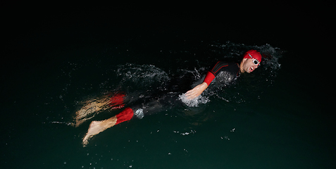 Image showing A determined professional triathlete undergoes rigorous night time training in cold waters, showcasing dedication and resilience in preparation for an upcoming triathlon swim competition