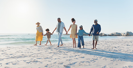 Image showing Holding hands, walking and big family at the beach on vacation, adventure or holiday together. Love, travel and children with parents and grandparents on the sand by the ocean or sea on weekend trip.