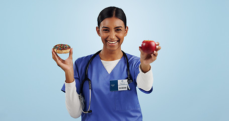Image showing Apple, donut and portrait of nurse with choice for healthy eating, diet and detox on blue background. Happy, healthcare and Indian woman with dessert, fruit and cake for decision, options and balance