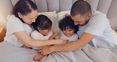 Image showing Laughing, tickling and parents with children in bed on a weekend morning in modern family home. Happy, fun and young mother and father relaxing, bonding and playing with kids in bedroom at house.