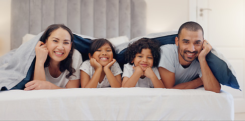 Image showing Portrait, smile and children with parents in bed relaxing and bonding together at family home. Happy, fun and young mother and father laying and resting with kids in bedroom of modern house.