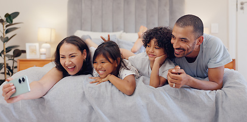 Image showing Selfie, smile and children with parents in bed relaxing and bonding together at family home. Happy, fun and young mother and father laying and taking a picture with kids in bedroom of modern house.