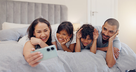 Image showing Happy, selfie and children with parents in bed relaxing and bonding together at family home. Smile, fun and young mother and father laying and taking a picture with kids in bedroom of modern house.