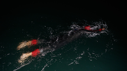 Image showing A determined professional triathlete undergoes rigorous night time training in cold waters, showcasing dedication and resilience in preparation for an upcoming triathlon swim competition