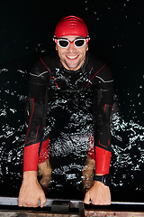 Image showing Authentic triathlete swimmer having a break during hard training on night